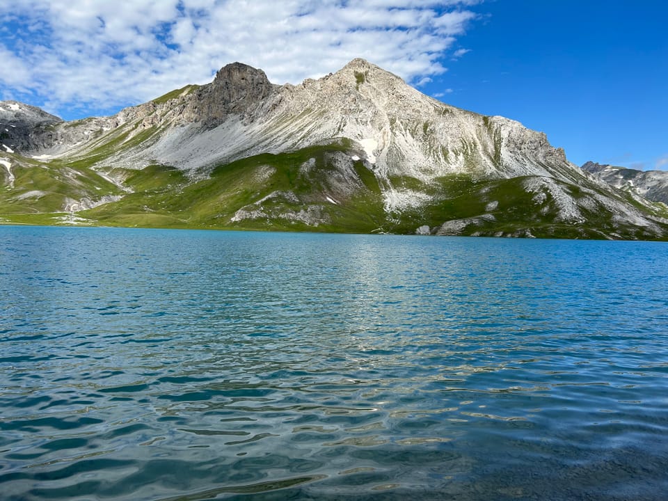 Bergsee mit Berglandschaft im Hintergrund.