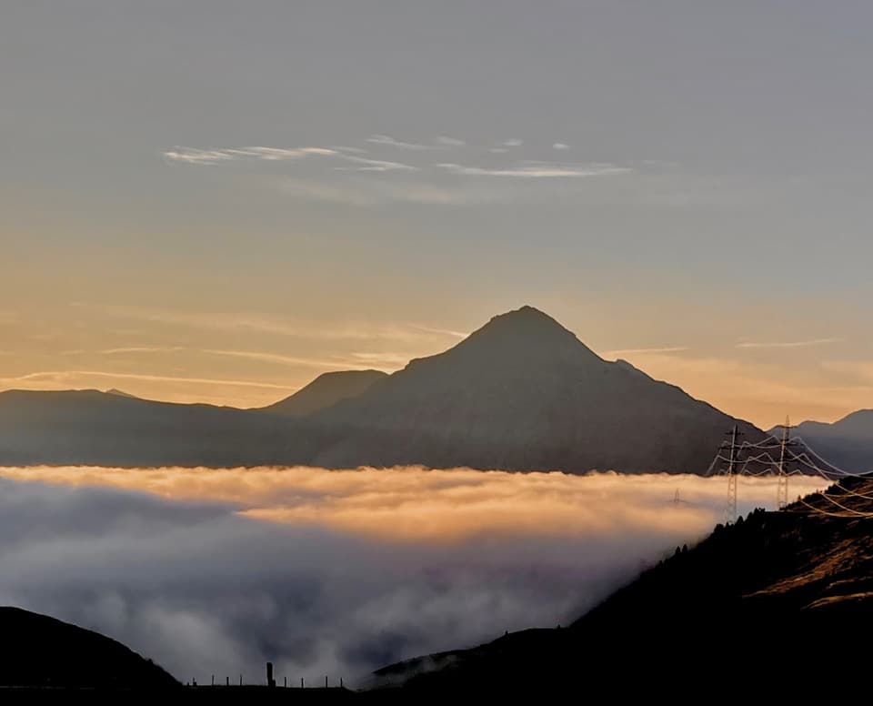 Berggipfel über Wolkendecke bei Sonnenuntergang.