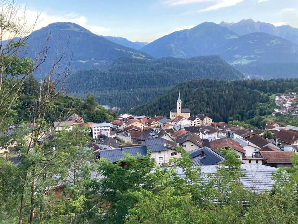 Dorf in den Alpen mit Kirche und Bergkulisse.