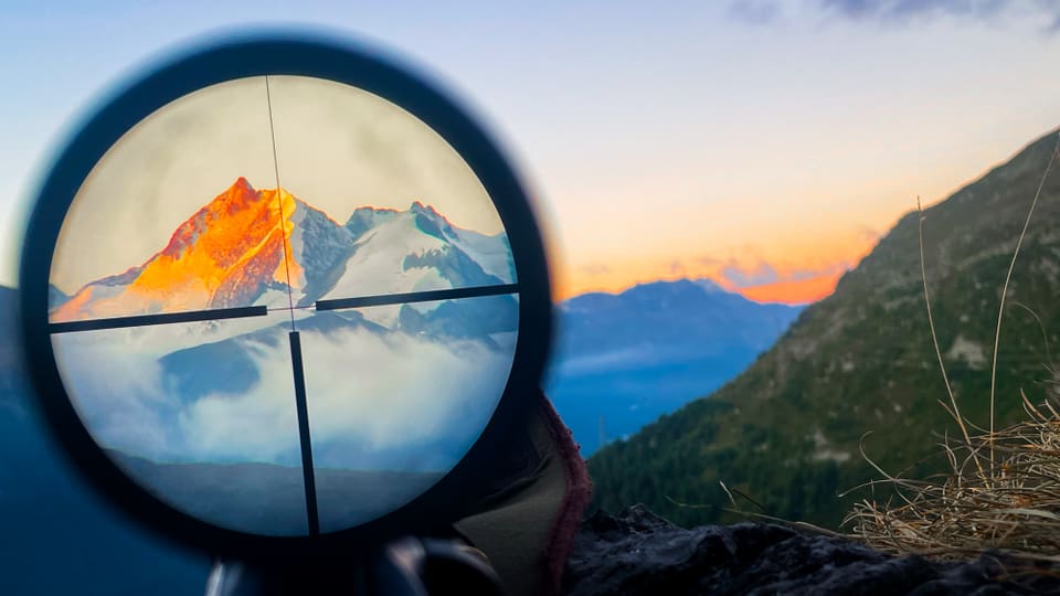 Berggipfel bei Sonnenuntergang durch Zielfernrohr gesehen.