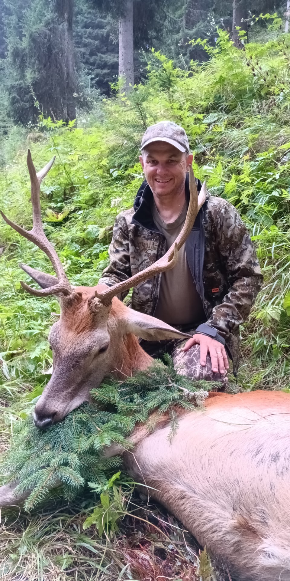 Jäger posiert mit erlegtem Hirsch im Wald.