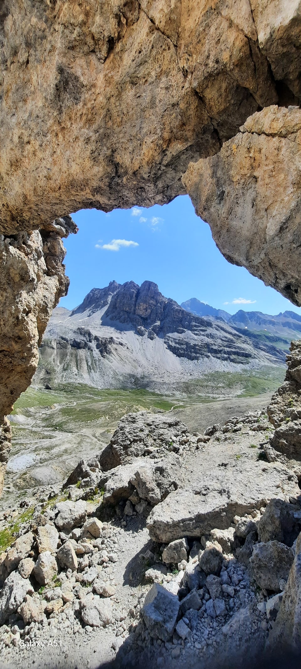 Blick durch eine felsige Öffnung auf eine Berglandschaft.