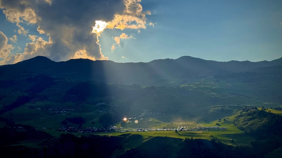 Landschaftsansicht mit Bergen und Feldern im Sonnenlicht.