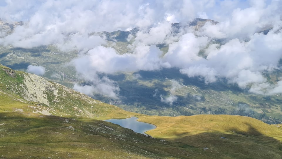 Berglandschaft mit Wolken und kleinem See.