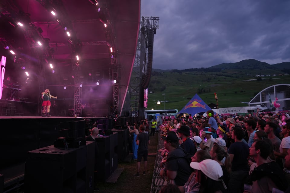 Konzertbühne mit Menschenmenge im Freien bei Sonnenuntergang am Open Air Lumnezia 2024.