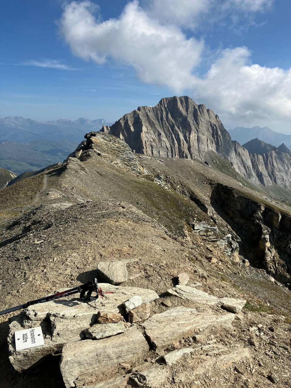 Bergpfad mit Gebirgskette im Hintergrund.