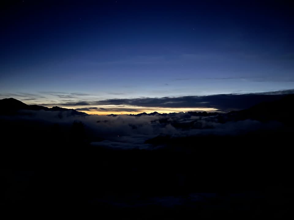 Berglandschaft bei Dämmerung mit Wolken und blauem Himmel.