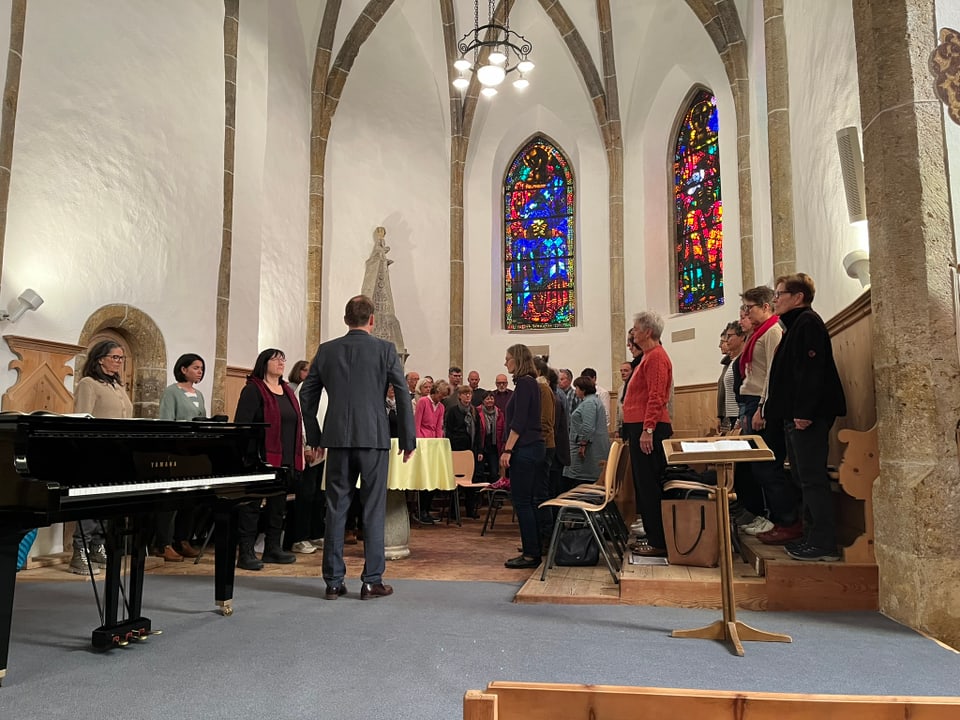 Chorprobe in einer Kirche mit bunten Glasfenstern.