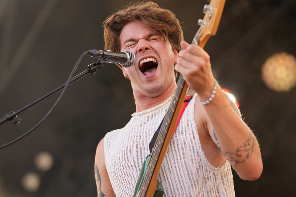 Musiker singt und spielt Bassgitarre auf der Bühne am Open Air Lumnezia 2024.