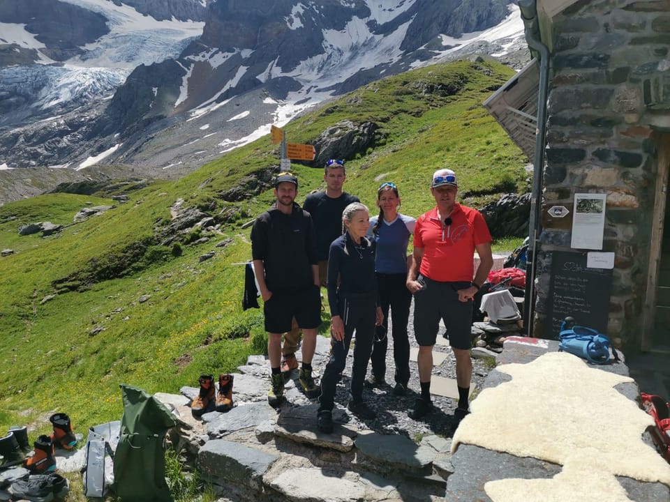 Fünf Personen vor einer Berghütte in den Alpen.