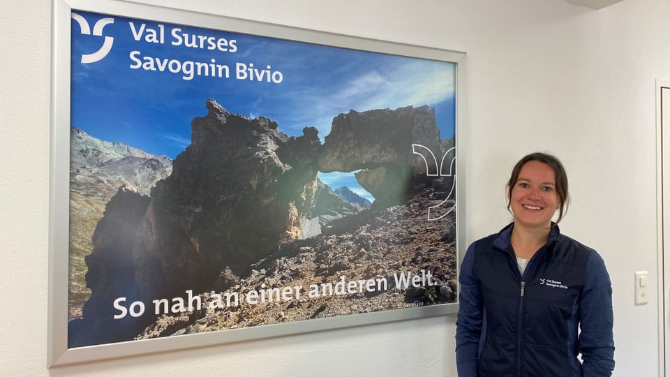 Frau steht neben einem grossen Poster von Val Surses Savognin Bivio.