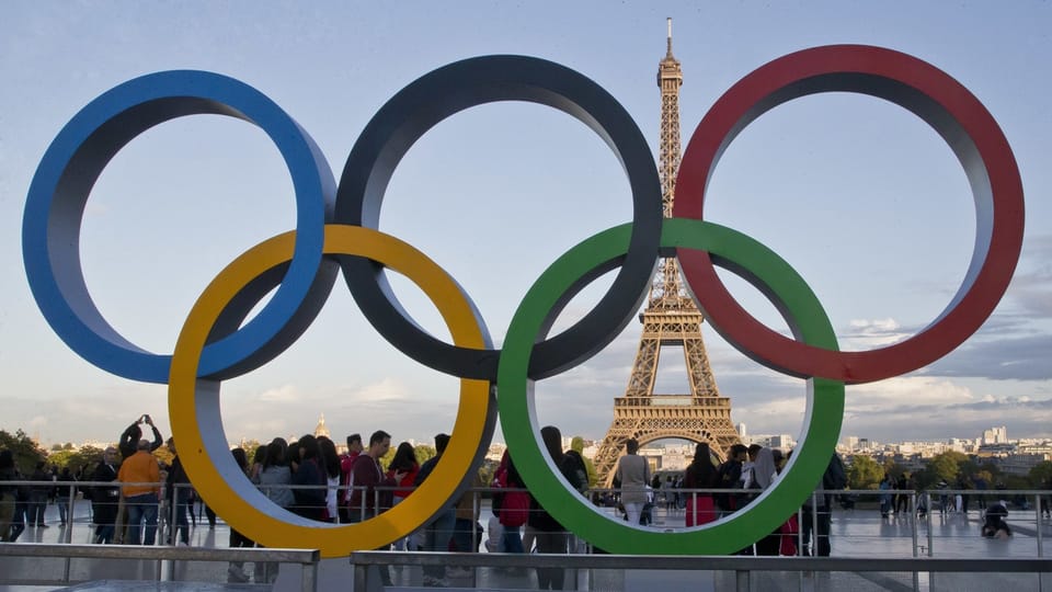 Paris 24 – Die olympischen Ringe mir Sicht auf den Eiffelturm.