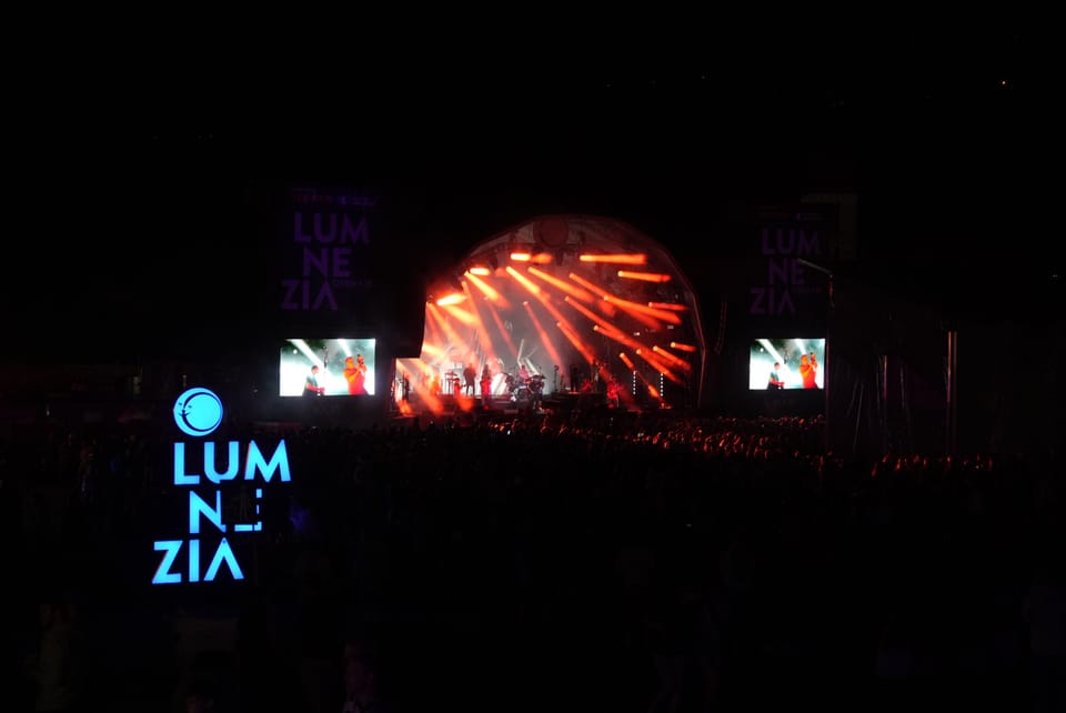 Bühne des Lumnezia-Musikfestivals mit Lichteffekten und Publikum bei Nacht.