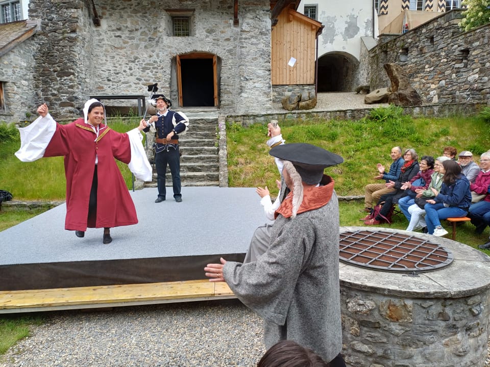 Eine historische Aufführung im Freien, bei der Schauspieler in Kostümen auf einer Bühne spielen.
