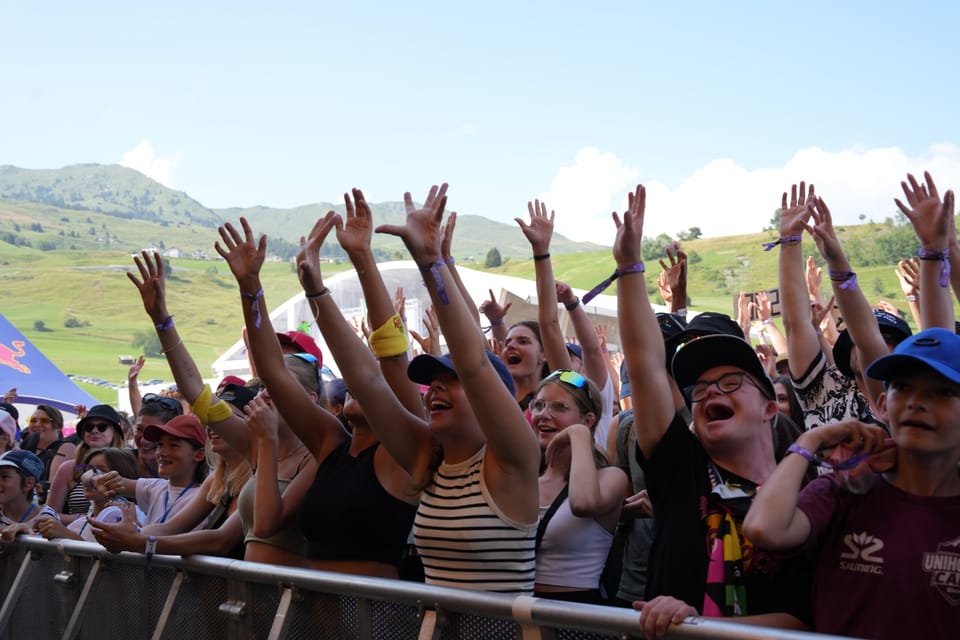 Menschenmenge bei einem Outdoor-Konzert mit erhobenen Händen.