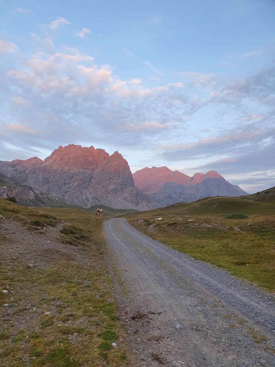 Schotterweg führt zu Berggipfeln bei Sonnenuntergang.