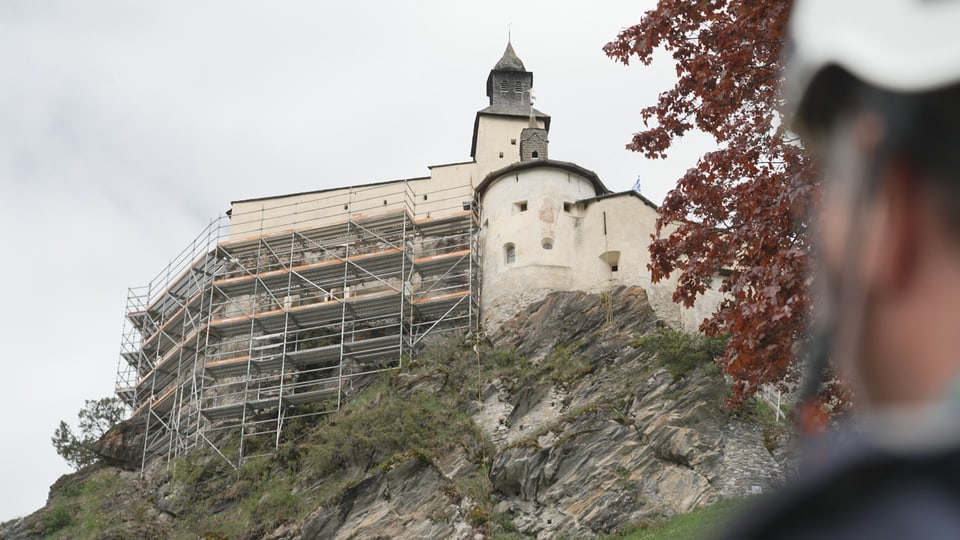 Schloss auf Felsvorsprung mit Baugerüst.