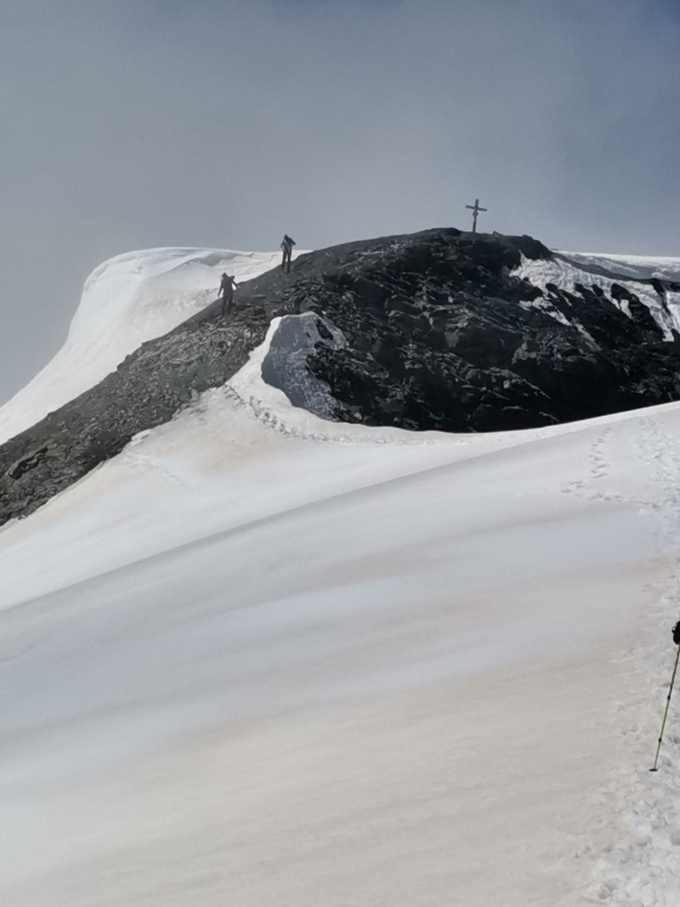 Besteigung: Piz Russein / Tödi: Bergsteiger auf schneebedecktem Gipfel mit Kreuz.