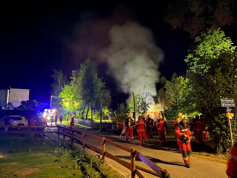 Feuerwehrleute bei Nacht im Einsatz bei einem Brand mit Rauchentwicklung.