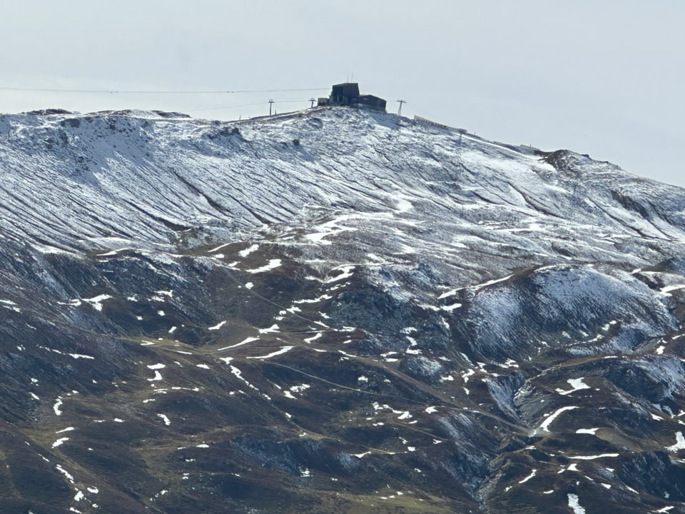 Verschneiter Berggipfel mit Gebäuden und Seilbahnen.