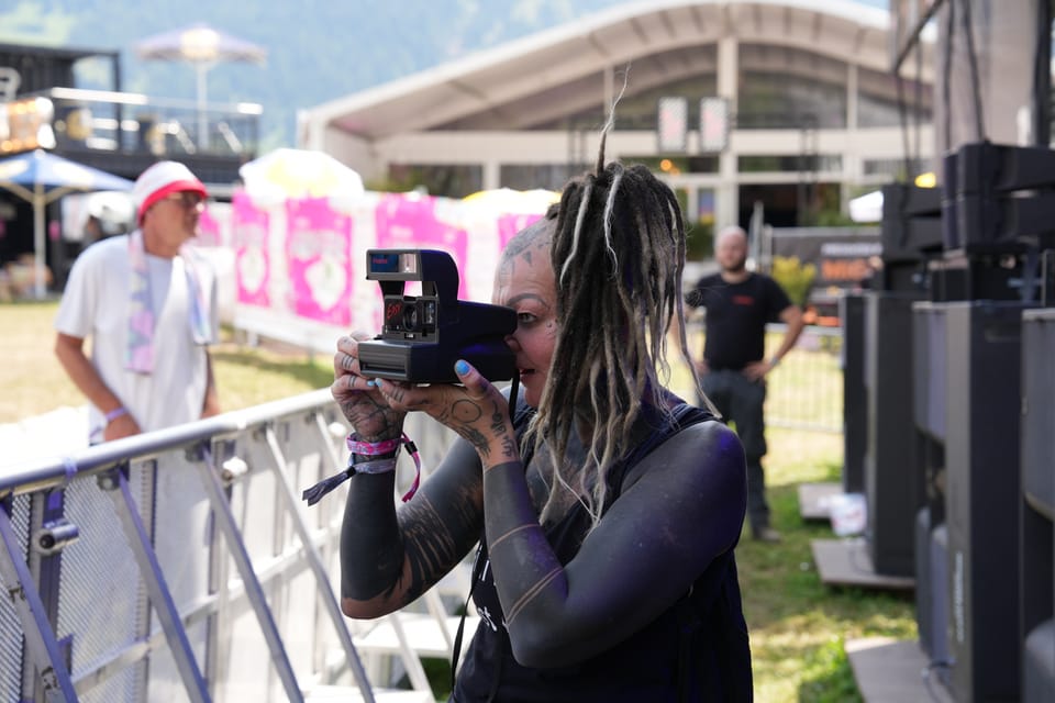 Frau mit Polaroid-Kamera bei Outdoor-Event am Open Air Lumnezia 2024 in Degen.