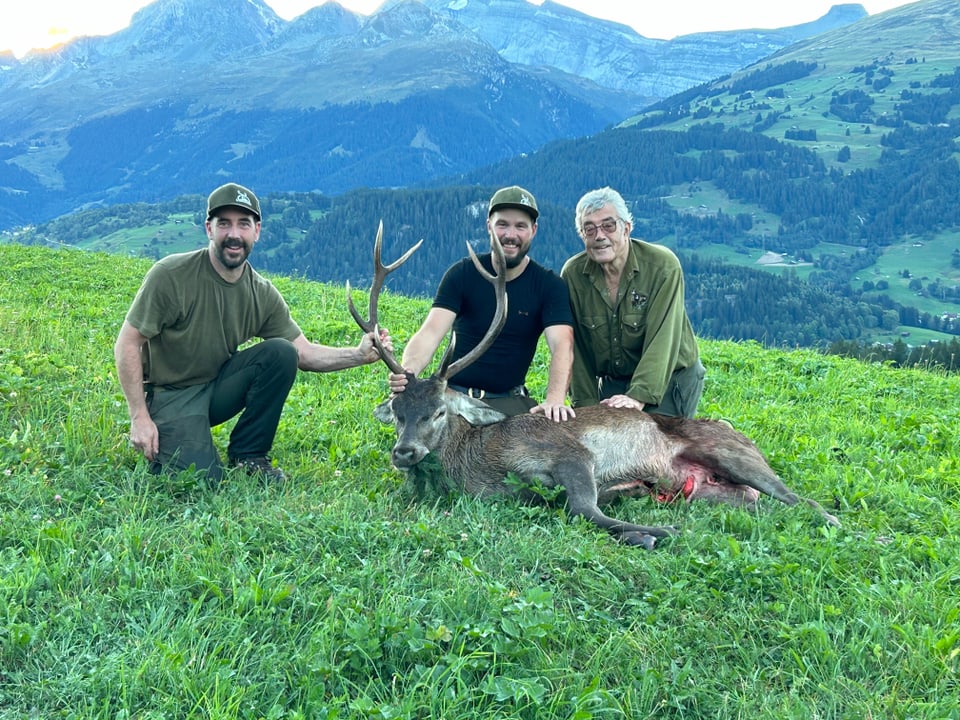 Drei Jäger mit einem geschossenen Hirsch.