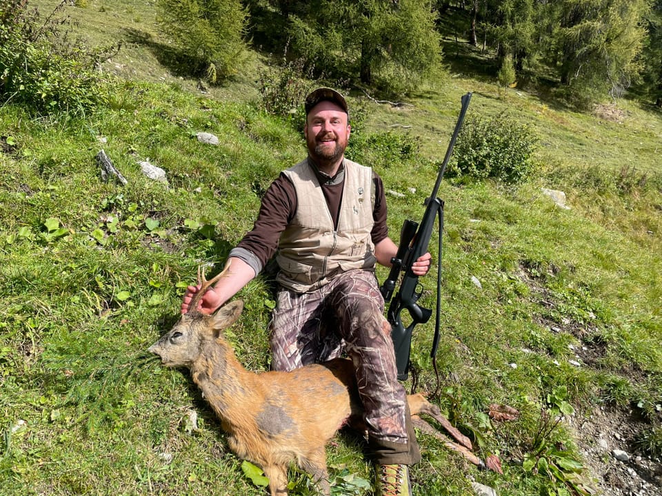 Jäger mit Gewehr neben erlegtem Reh in der Natur.